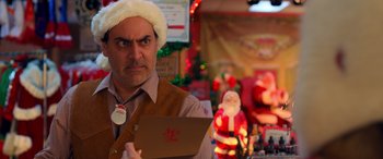 Movie still from “Noelle” (2019), directed by Marc Lawrence – A man wearing a santa hat and holding an envelope; Close Up shot, Over the shoulder angle