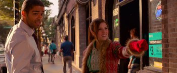 Movie still from “Noelle” (2019), directed by Marc Lawrence – A young woman in a fur trimmed coat walking down the street; Medium shot, Over the shoulder angle