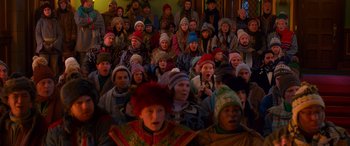Movie still from “Noelle” (2019), directed by Marc Lawrence – A group of people wearing winter hats in front of a crowd; Medium shot, High angle