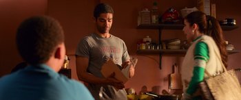 Movie still from “Noelle” (2019), directed by Marc Lawrence – A man holding a box in a kitchen; Medium shot, Over the shoulder angle