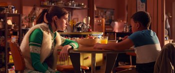 Movie still from “Noelle” (2019), directed by Marc Lawrence – Two people sitting at a table with a bowl of orange juice; Medium shot, Over the shoulder angle