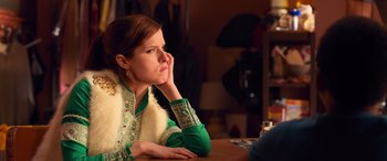 Movie still from “Noelle” (2019), directed by Marc Lawrence – A woman sitting at a table with her chin resting on her hand; Medium shot, Over the shoulder angle