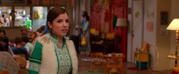 Movie still from “Noelle” (2019), directed by Marc Lawrence – A woman in a green and white dress standing in a living room; Close Up shot, Over the shoulder angle