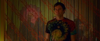 Movie still from “Noelle” (2019), directed by Marc Lawrence – A man standing in front of a colorful wall; Medium shot, Over the shoulder angle