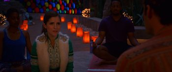 Movie still from “Noelle” (2019), directed by Marc Lawrence – A woman sitting on the ground next to a man in front of candles; Medium shot, Over the shoulder angle