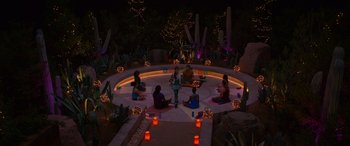 Movie still from “Noelle” (2019), directed by Marc Lawrence – A group of people sitting in a circle at night; Extreme Wide shot, High angle