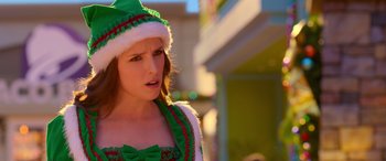 Movie still from “Noelle” (2019), directed by Marc Lawrence – A woman wearing a green and red dress and a green and white hat; Close Up shot, Over the shoulder angle