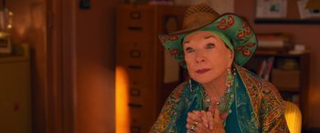 Movie still from “Noelle” (2019), directed by Marc Lawrence – An older woman wearing a cowboy hat with her hands clasped together; Close Up shot, Over the shoulder angle