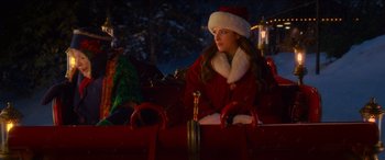Movie still from “Noelle” (2019), directed by Marc Lawrence – A woman sitting in the back of a horse drawn carriage wearing a santa clause hat; Medium shot, Over the shoulder angle