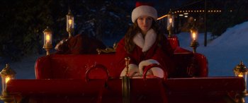 Movie still from “Noelle” (2019), directed by Marc Lawrence – A woman sitting in the back of a fire truck wearing a santa claus hat; Medium shot, High angle