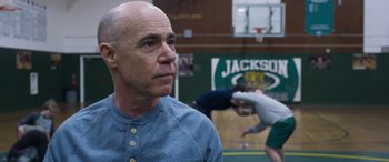 Movie still from “Notorious Nick” (2021), directed by Aaron Leong – An older bald man is standing in a gym; Close Up shot, Low angle