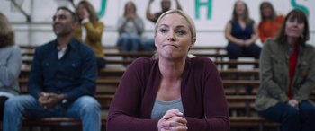Movie still from “Notorious Nick” (2021), directed by Aaron Leong – A woman sitting in front of a group of people in a gym; Close Up shot, Over the shoulder angle
