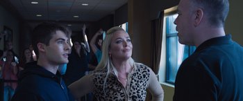 Movie still from “Notorious Nick” (2021), directed by Aaron Leong – A woman standing in front of a group of people; Medium shot, Over the shoulder angle