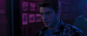 Movie still from “Notorious Nick” (2021), directed by Aaron Leong – A young man in a plaid shirt stares into the camera; Close Up shot, Low angle