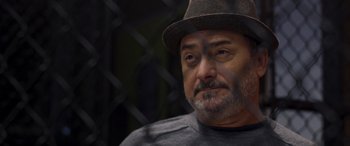 Movie still from “Notorious Nick” (2021), directed by Aaron Leong – A person wearing a hat and looking at the camera; Close Up shot, Low angle