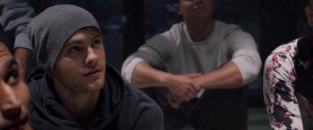 Movie still from “Notorious Nick” (2021), directed by Aaron Leong – Two young men sitting next to each other in a dark room; Close Up shot, Over the shoulder angle