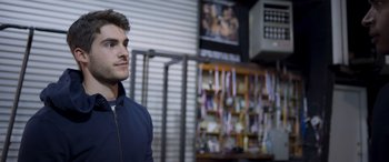 Movie still from “Notorious Nick” (2021), directed by Aaron Leong – A man standing in a room next to shelves; Close Up shot, Over the shoulder angle