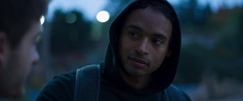 Movie still from “Notorious Nick” (2021), directed by Aaron Leong – A young man wearing a hooded sweatshirt looks into the camera; Close Up shot, Low angle