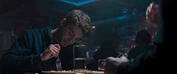 Movie still from “Notorious Nick” (2021), directed by Aaron Leong – A man sitting at a table with a fork in his hand; Close Up shot, Over the shoulder angle