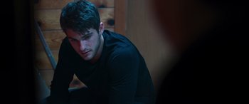 Movie still from “Notorious Nick” (2021), directed by Aaron Leong – A man sitting in front of a wooden wall; Close Up shot, Over the shoulder angle