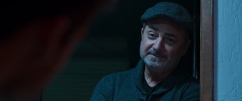 Movie still from “Notorious Nick” (2021), directed by Aaron Leong – A person wearing a hat; Close Up shot, Over the shoulder angle