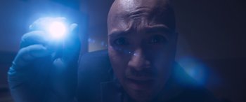 Movie still from “Notorious Nick” (2021), directed by Aaron Leong – A bald man with blue light shining on his face; Extreme Close Up shot, Low angle