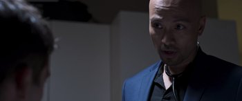 Movie still from “Notorious Nick” (2021), directed by Aaron Leong – A man in a blue jacket and a black shirt; Close Up shot, Low angle