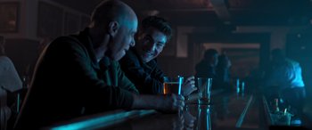 Movie still from “Notorious Nick” (2021), directed by Aaron Leong – Two men sitting at a bar with a drink in front of them; Medium shot, Over the shoulder angle