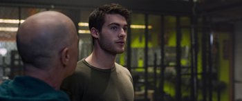 Movie still from “Notorious Nick” (2021), directed by Aaron Leong – A young man is looking into the distance while standing in a room; Close Up shot, Over the shoulder angle