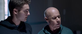 Movie still from “Notorious Nick” (2021), directed by Aaron Leong – A man and a boy standing next to each other; Close Up shot, Low angle