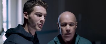 Movie still from “Notorious Nick” (2021), directed by Aaron Leong – A man and another man are standing next to each other; Close Up shot, Low angle