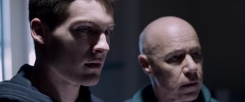Movie still from “Notorious Nick” (2021), directed by Aaron Leong – A man and a bald man looking at each other; Close Up shot, Over the shoulder angle