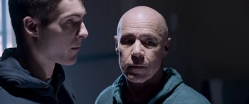 Movie still from “Notorious Nick” (2021), directed by Aaron Leong – A man with a shaved head and a man with a shaved head looking at him; Close Up shot, Over the shoulder angle