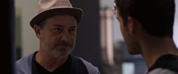 Movie still from “Notorious Nick” (2021), directed by Aaron Leong – A man wearing a hat talking to another man; Close Up shot, Over the shoulder angle