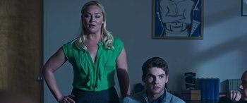 Movie still from “Notorious Nick” (2021), directed by Aaron Leong – A man and a woman are sitting in a living room; Medium shot, Over the shoulder angle