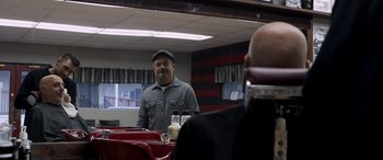 Movie still from “Notorious Nick” (2021), directed by Aaron Leong – A man standing in front of a mirror in a barber shop; Medium shot, Over the shoulder angle