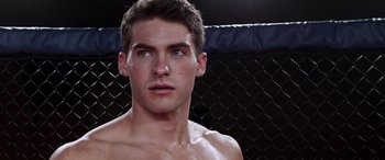 Movie still from “Notorious Nick” (2021), directed by Aaron Leong – A man's face in front of a chain link fence; Close Up shot, Over the shoulder angle