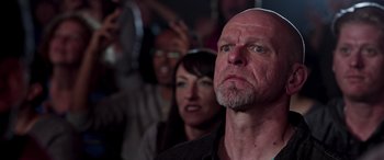 Movie still from “Notorious Nick” (2021), directed by Aaron Leong – An older man with a goatee looks up into the sky; Close Up shot, Low angle