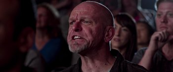 Movie still from “Notorious Nick” (2021), directed by Aaron Leong – An older bald man with a goatee is looking at the camera; Close Up shot, Low angle