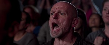 Movie still from “Notorious Nick” (2021), directed by Aaron Leong – An old man with a bald head and a goatee is screaming; Close Up shot, Low angle