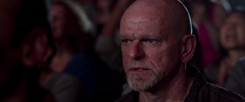 Movie still from “Notorious Nick” (2021), directed by Aaron Leong – An older man with a shaved head and a goatee; Close Up shot, Over the shoulder angle