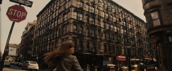 Movie still from “Now You See Me” (2013), directed by Louis Leterrier – A woman riding a bike down a street past tall buildings; Wide shot, Low angle