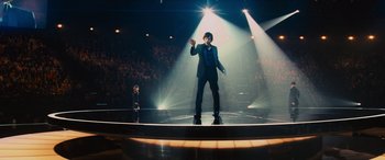 Movie still from “Now You See Me” (2013), directed by Louis Leterrier – A man standing on a stage in front of an audience; Wide shot, Low angle