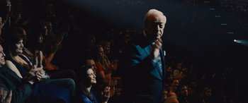 Movie still from “Now You See Me” (2013), directed by Louis Leterrier – An older man standing in front of an audience; Medium shot, Over the shoulder angle