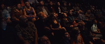 Movie still from “Now You See Me” (2013), directed by Louis Leterrier – A group of people sitting in a room watching a show; Medium shot, High angle