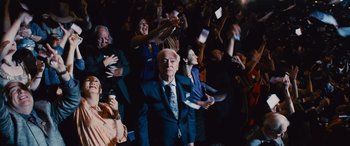 Movie still from “Now You See Me” (2013), directed by Louis Leterrier – A group of people in a room with hands raised; Medium shot, Over the shoulder angle