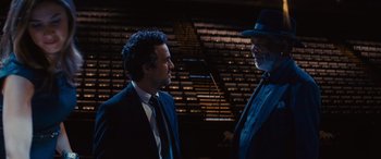 Movie still from “Now You See Me” (2013), directed by Louis Leterrier – Two men in suits and a hat talking to each other in front of an audience; Medium shot, Over the shoulder angle