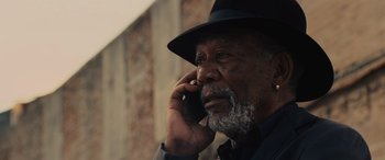 Movie still from “Now You See Me” (2013), directed by Louis Leterrier – An older man talking on a cell phone while wearing a hat; Close Up shot, Low angle