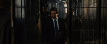 Movie still from “Now You See Me” (2013), directed by Louis Leterrier – A man in a suit and tie standing in front of a jail cell; Medium shot, Low angle