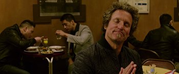 Movie still from “Now You See Me 2” (2016), directed by Jon M. Chu – A man sitting in front of another man drinking a beverage; Close Up shot, Over the shoulder angle